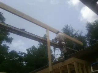 Carpenter setting a ridge beam over a new addition frame — Ice Dam Removal by Roofing Brothers in Dexter
